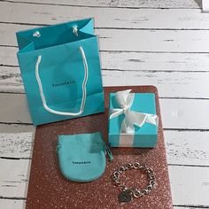 a blue gift bag, bracelet and ring sitting on a table next to a box