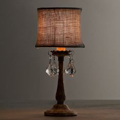 a lamp that is sitting on top of a wooden table with a brown shade over it