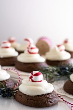 chocolate cookies with white frosting and candy canes on top are sitting on a table