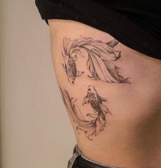 a woman's stomach with fish tattoo on it