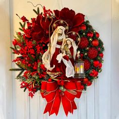 a wreath hanging on the front door decorated with red flowers and an image of virgin mary