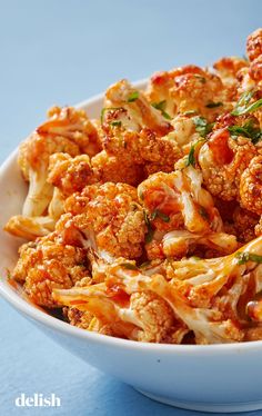 a white bowl filled with pasta covered in sauce and meatballs on top of a blue table