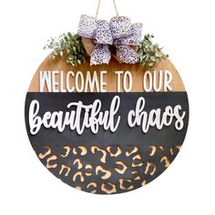 a sign that says welcome to our beautiful chaos with leopard print on it and a bow