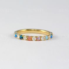 a yellow gold ring with multicolored opal and diamond stones on the side