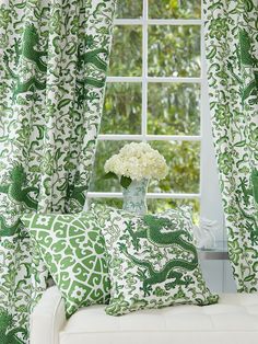 a white couch sitting next to a window covered in green and white curtained curtains