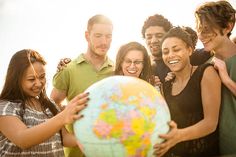 a group of young people standing around a globe smiling at the camera stock - fotor