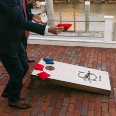 a man standing next to a giant cornhole game on top of a brick walkway