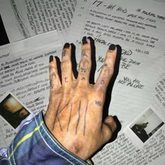 a hand with tattoos on it sitting in front of some sheets of paper and papers