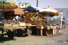 an open air market with fruit and vegetables on the back of a flatbed truck