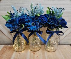 three vases filled with blue flowers on top of a wooden table