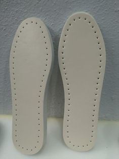 a pair of white shoes with holes on the soles are sitting next to each other