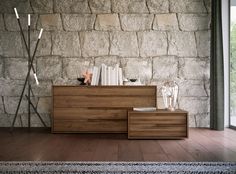 a wooden dresser sitting in front of a stone wall next to a lamp and bookshelf