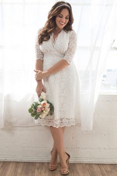 a woman standing in front of a window holding a bouquet