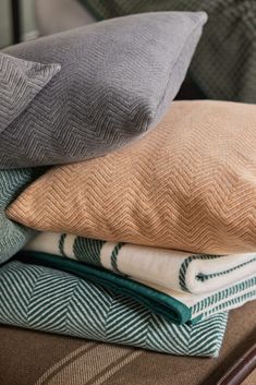 four pillows stacked on top of each other in different colors and patterns, with one folded down