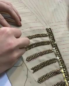 a person is working on some gold colored metal pieces with chains attached to the sides