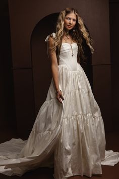 a woman in a long white dress posing for a photo with her hands on her hips