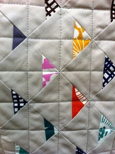 a close up of a quilted piece of fabric with different colored triangles on it