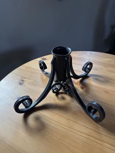 an iron candle holder sitting on top of a wooden table