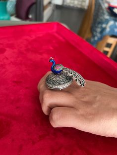 Elevate your style with our exquisite 925 silver peacock ring, handcrafted by skilled Indian artisans. This one-of-a-kind piece features a captivating rotating peacock design adorned with intricate stone and enamel work. Designed to stand out, this ring brings the beauty of the peacock to life, with every detail reflecting the artistry of India's heritage. Wear a symbol of grace and elegance while celebrating the essence of motion and creativity. Embrace the craftsmanship that makes this ring tr Handmade Peacock Colored Jewelry For Weddings, Silver Peacock Design Jewelry For Party, Handmade Peacock Wedding Jewelry, Elegant Peacock Design Jewelry Ring, Elegant Peacock Design Ring, Elegant Peacock Design Rings As Gift, Elegant Peacock Design Rings For Gifts, Unique Peacock Design Wedding Jewelry, Wedding Rings With Peacock Design