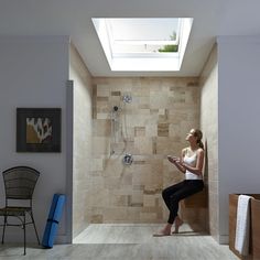 a woman is sitting in the shower with her feet up on the floor and looking up at the skylight