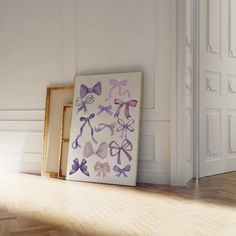 an empty room with two framed pictures on the floor and one has purple bows painted on it