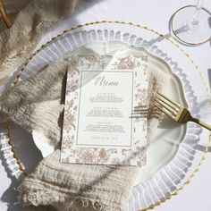 a plate with a menu on it sitting next to a fork and napkin, along with some wine glasses