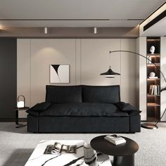 a living room filled with black furniture and bookshelves next to a white wall