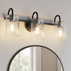 a bathroom vanity with three lights and a round mirror