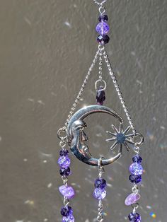 a wind chime with purple beads hanging from it's side and a star on the top