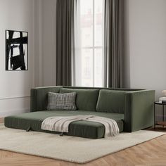 a green couch sitting on top of a white rug in front of a large window