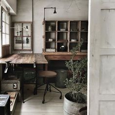 a room with a desk, chair and potted plant on the table in it