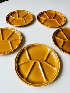 four yellow plates sitting on top of a white table