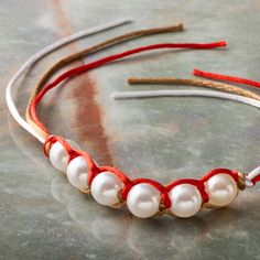 a close up of a headband with pearls and red string on top of a table