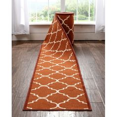 an orange and white runner rug in front of a window