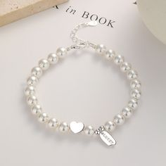 This stunning piece features a delicate strand of lustrous pearls, gracefully encircling your wrist. Nestled in the center, a shimmering silver heart adds a touch of romance, while a finely crafted pendant, engraved with the word "lucky," dangles gracefully, radiating positive energy. Adorn yourself with this timeless treasure, as it embodies the essence of beauty and fortune. Each pearl represents the wisdom gained from life's precious moments, while the silver heart symbolizes love and compass Pearl Fashion, White Pearl Bracelet, Bracelet Online, The Wisdom, Bracelet Argent, Timeless Treasures, Sterling Silver Bracelet, Precious Moments, White Pearl