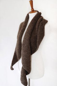 a brown knitted scarf hanging on a white mannequin