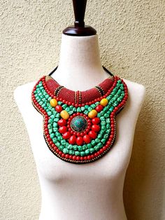 "Striking Tibetan turquoise and coral bib collar necklace in faux teal green turquoise, coral beads, with a stunning central brass medallion. Perfect with a flowing caftan or an itsy black bikini. Perfect anywhere you are barefoot! Wear your hair up, with a bright ribbon or turban, or wear it down! You don't need much else! Eye-catching geometric pattern with a mix of smooth and textured beads. This is a handmade reproduction of a Tibetan tribal neck piece or Skeypuk, which is worn as collars on Bohemian Turquoise Bib Necklace With Colorful Beads, Bohemian Red Bib Necklace With Round Beads, Handmade Turquoise Bohemian Bib Necklace, Red Bohemian Bib Necklace For Festivals, Red Beaded Bohemian Bib Necklaces, Bohemian Bib Necklace With Colorful Beads, Green Bohemian Beaded Necklaces, Bohemian Beaded Necklaces With Round Beads, Bohemian Beaded Necklace With Round Beads