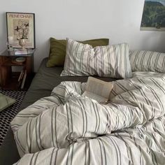 an unmade bed with striped sheets and pillows