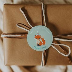 a gift wrapped in brown paper with a fox sticker on it's side