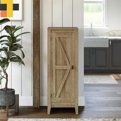 a wooden cabinet sitting next to a potted plant in a room with white walls