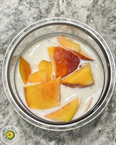 a glass bowl filled with fruit on top of a marble countertop next to a spoon