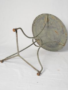 an old metal object with two legs and a round plate on it's stand