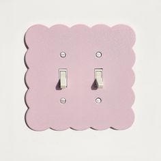 two light switches on a pink wall with scalloped edges and one switch plate