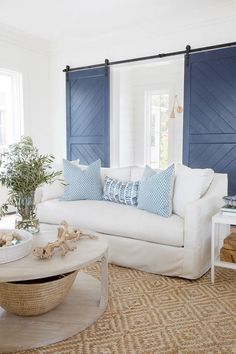 a living room with white furniture and blue shutters