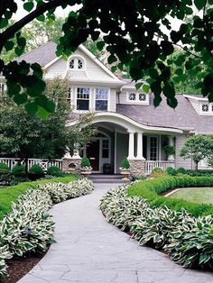 a large house surrounded by lush green trees and shrubbery in front of the entrance