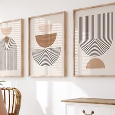 three framed art pieces hang on the wall above a white table and chair in front of a window