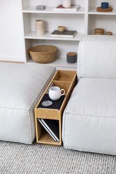 a white couch with a coffee cup on it next to a book shelf filled with books