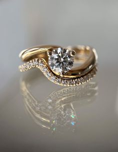 a close up view of a gold ring with a diamond in the middle and two rows of diamonds on each band