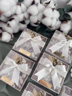 four boxes filled with cotton sitting on top of a table next to some white flowers