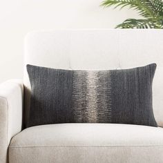 a black and white pillow sitting on top of a couch next to a potted plant